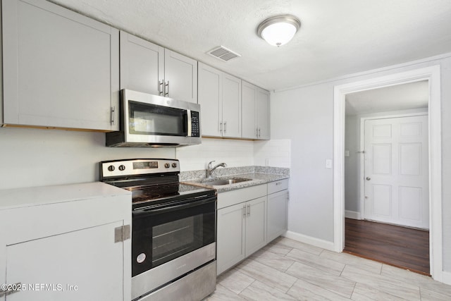 kitchen featuring tasteful backsplash, appliances with stainless steel finishes, sink, and a textured ceiling