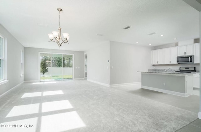 kitchen with range, white cabinetry, a notable chandelier, a center island with sink, and decorative light fixtures