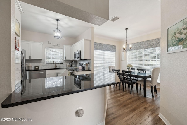 kitchen with white cabinetry, appliances with stainless steel finishes, decorative light fixtures, and kitchen peninsula