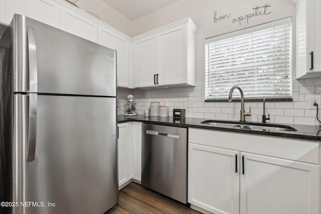 kitchen with white cabinetry, appliances with stainless steel finishes, sink, and dark stone counters