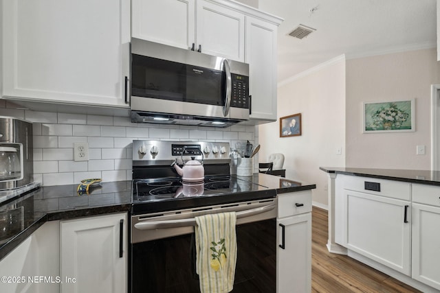 kitchen featuring white cabinetry, crown molding, tasteful backsplash, light wood-type flooring, and appliances with stainless steel finishes