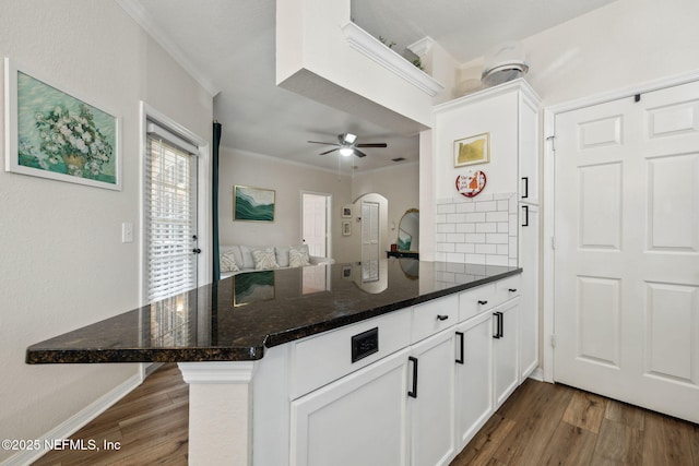 kitchen featuring dark stone counters, dark hardwood / wood-style flooring, kitchen peninsula, and white cabinets