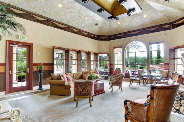 living room with plenty of natural light, a towering ceiling, and light carpet