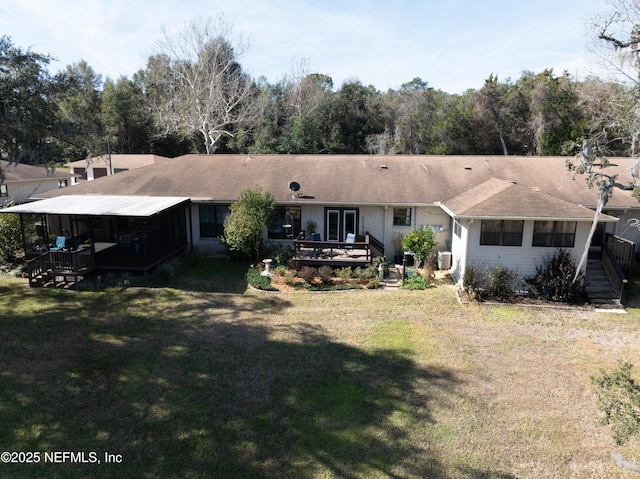 back of property featuring a wooden deck and a yard