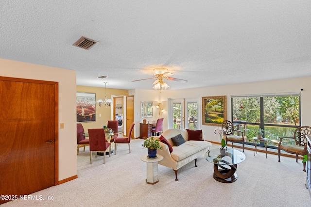 carpeted living room featuring washer / clothes dryer, ceiling fan with notable chandelier, and a textured ceiling