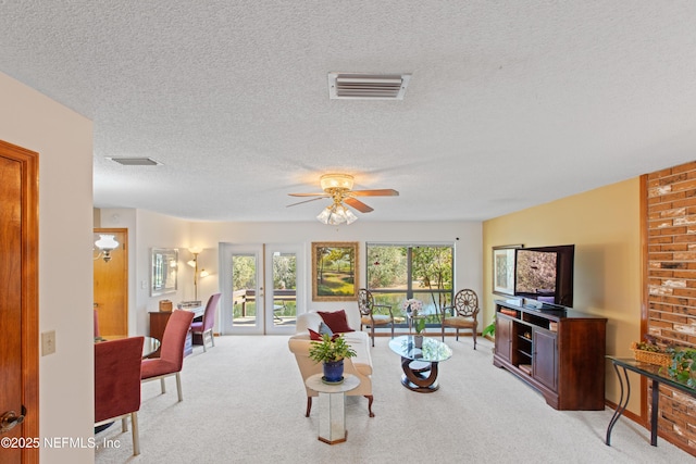 living room with light carpet, ceiling fan, and a textured ceiling