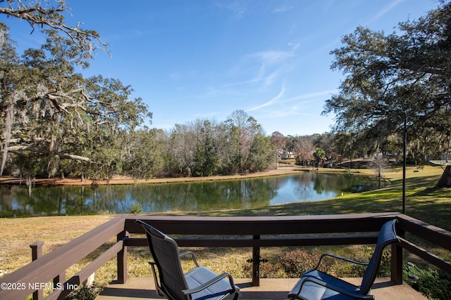 wooden terrace with a water view and a lawn