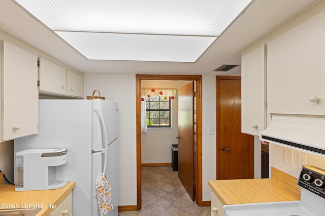 kitchen featuring white fridge, range, and white cabinets