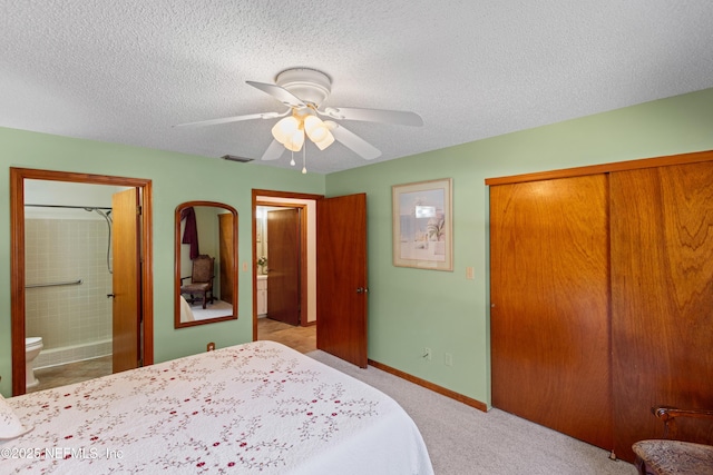 bedroom featuring ensuite bathroom, light colored carpet, ceiling fan, a textured ceiling, and a closet