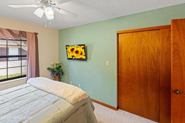 carpeted bedroom with ceiling fan, a closet, and a textured ceiling