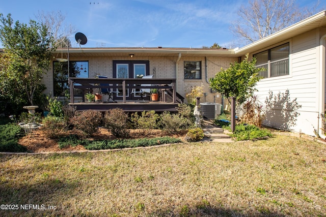 back of property with a wooden deck, central AC unit, and a lawn