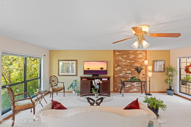 carpeted living room with ceiling fan, a wealth of natural light, and a textured ceiling