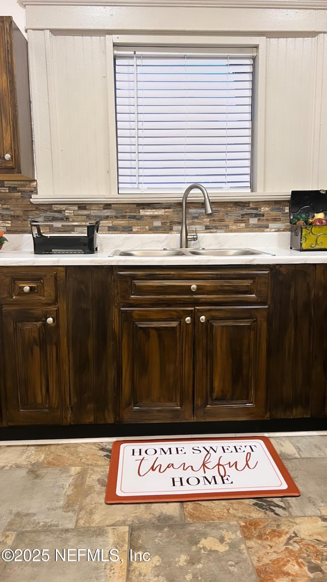 kitchen featuring light countertops, a sink, and dark brown cabinetry