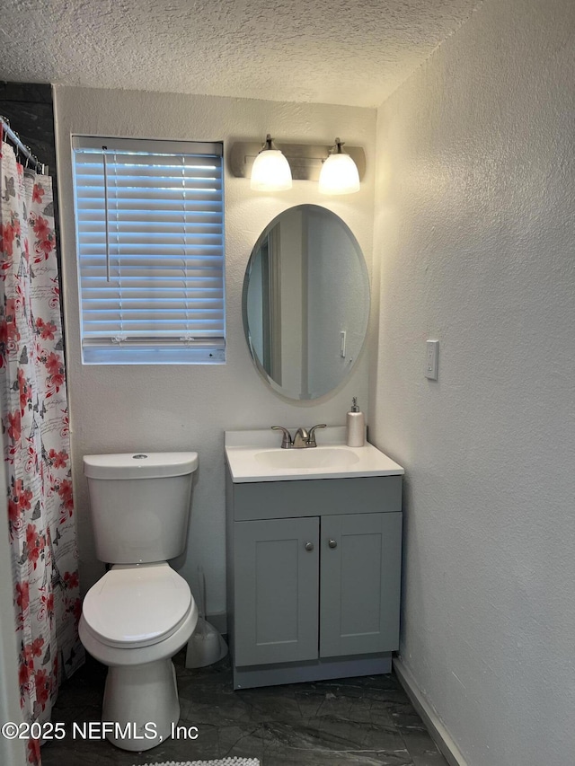 bathroom featuring a textured ceiling, a textured wall, curtained shower, toilet, and vanity