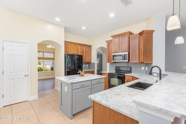 kitchen with gray cabinets, pendant lighting, a center island, black appliances, and light stone countertops