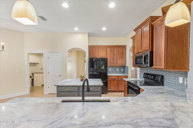 kitchen with pendant lighting, light tile patterned floors, sink, and black appliances