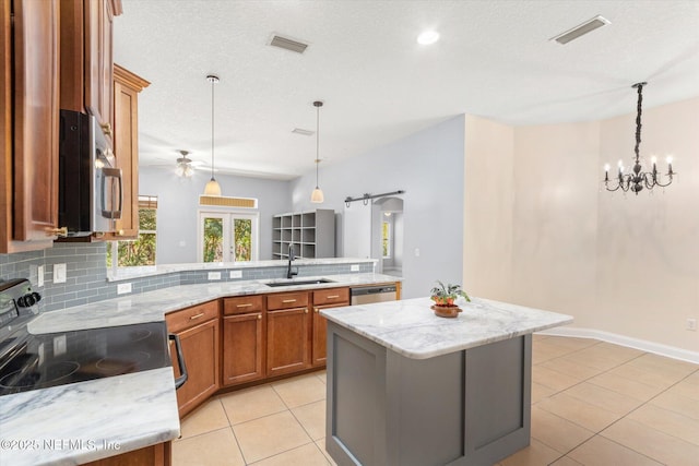 kitchen featuring stainless steel appliances, decorative light fixtures, a center island, and sink