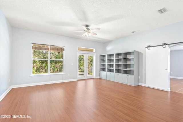 unfurnished living room featuring hardwood / wood-style floors, a textured ceiling, french doors, and ceiling fan