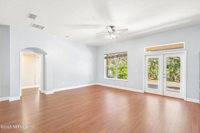 empty room featuring hardwood / wood-style floors, a textured ceiling, french doors, and ceiling fan