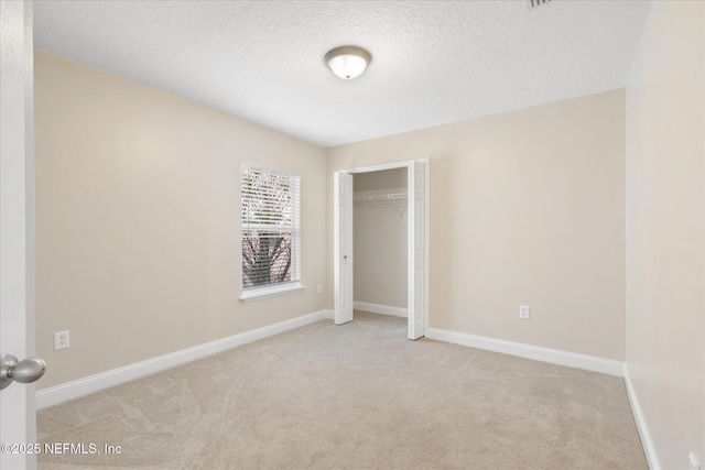 unfurnished bedroom with light colored carpet, a closet, and a textured ceiling