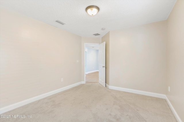 unfurnished room featuring light colored carpet and a textured ceiling