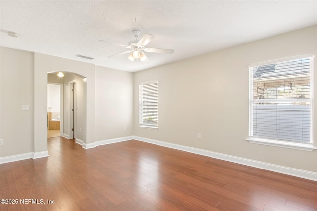 empty room featuring ceiling fan, a textured ceiling, and dark hardwood / wood-style flooring