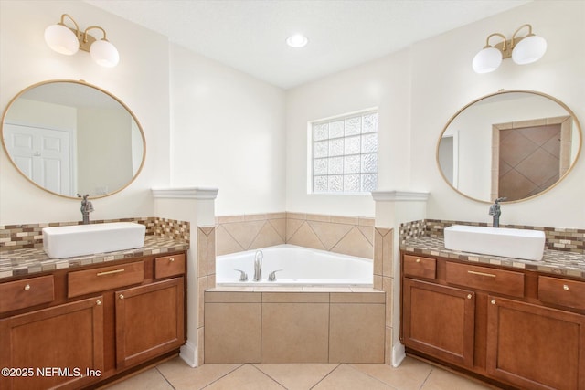 bathroom featuring a relaxing tiled tub, vanity, and tile patterned floors