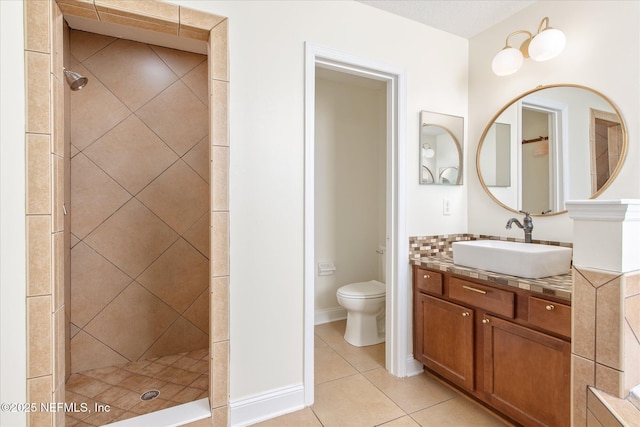 bathroom featuring tile patterned floors, toilet, vanity, and a tile shower