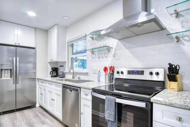 kitchen with stainless steel appliances, white cabinetry, light stone countertops, and range hood