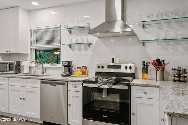 kitchen featuring sink, appliances with stainless steel finishes, white cabinets, range hood, and backsplash