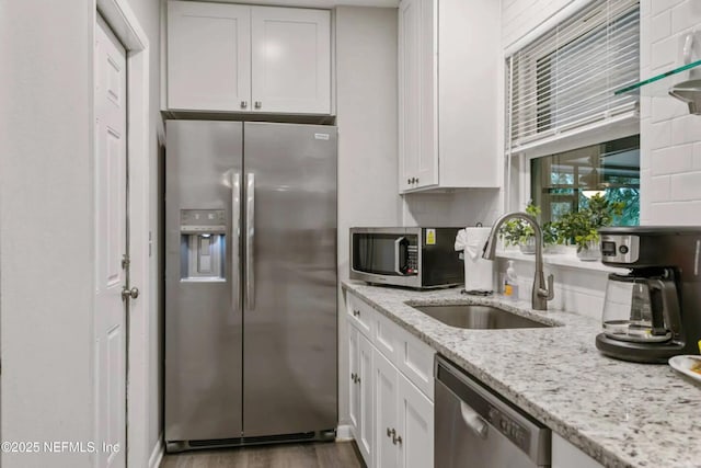 kitchen with sink, appliances with stainless steel finishes, dark hardwood / wood-style floors, light stone countertops, and white cabinets