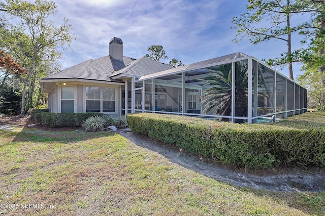 rear view of house with a yard and glass enclosure