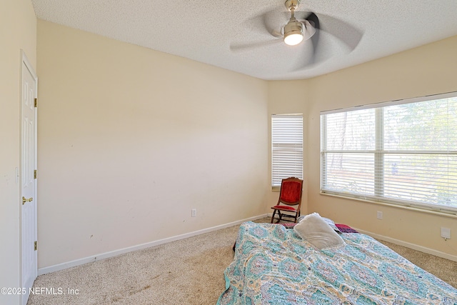 bedroom featuring ceiling fan, light colored carpet, and a textured ceiling