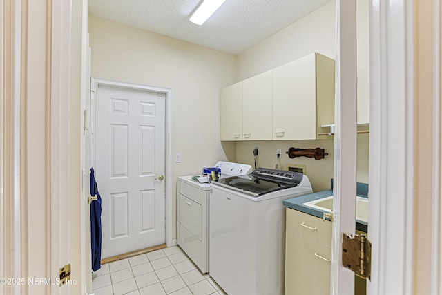 laundry room featuring independent washer and dryer, light tile patterned floors, cabinets, and a textured ceiling