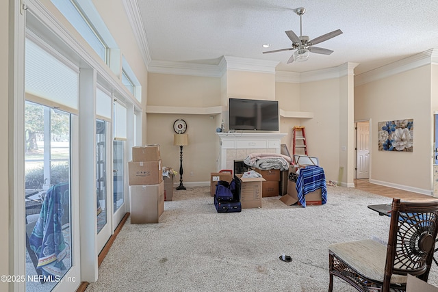 carpeted living room featuring ceiling fan, a towering ceiling, a fireplace, ornamental molding, and a textured ceiling