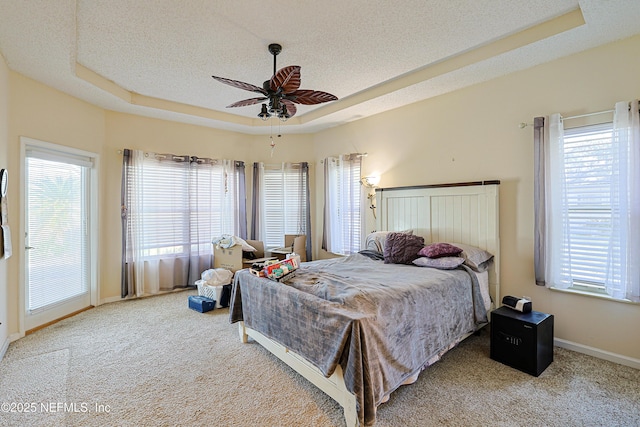 bedroom featuring ceiling fan, a tray ceiling, carpet floors, and a textured ceiling