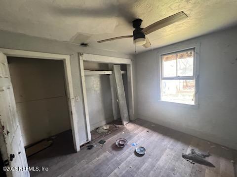 unfurnished bedroom with hardwood / wood-style flooring, ceiling fan, and a closet