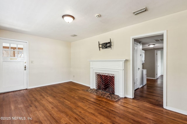 unfurnished living room featuring visible vents, a fireplace, baseboards, and wood finished floors