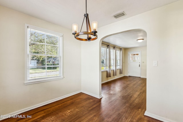 unfurnished dining area featuring arched walkways, a healthy amount of sunlight, visible vents, and dark wood finished floors