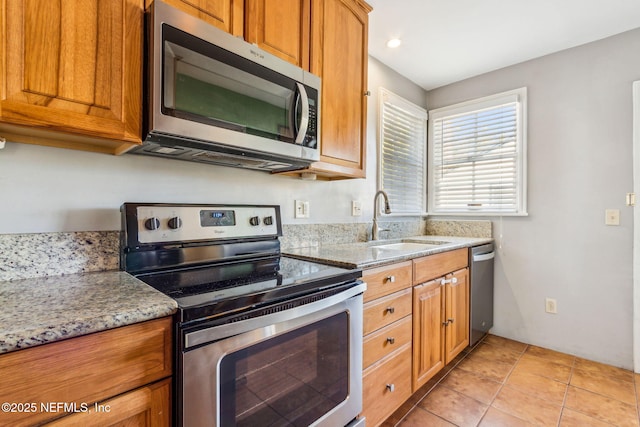 kitchen featuring appliances with stainless steel finishes, brown cabinetry, and light stone counters