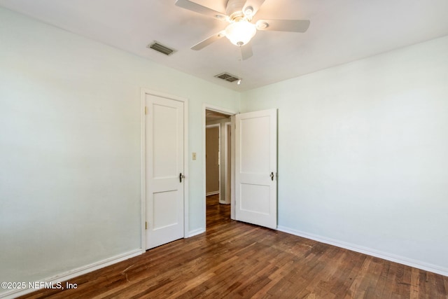 spare room with baseboards, visible vents, ceiling fan, and wood finished floors