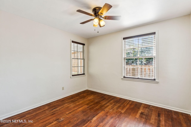 unfurnished room with dark wood finished floors, a ceiling fan, and baseboards