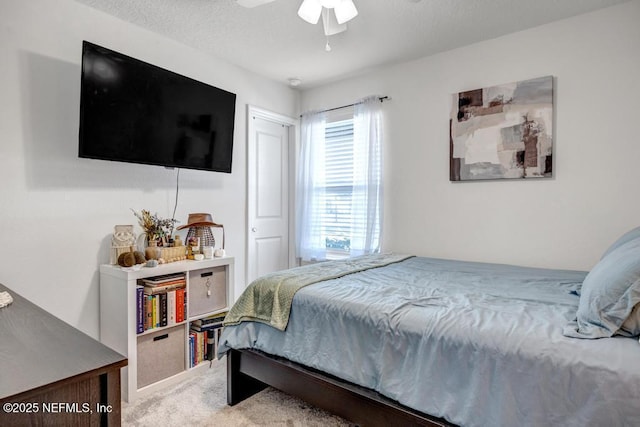 carpeted bedroom with ceiling fan and a textured ceiling