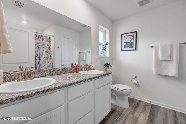 bathroom with hardwood / wood-style flooring, vanity, a shower with shower curtain, and toilet