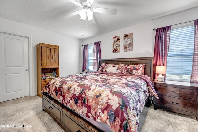 bedroom featuring ceiling fan, light colored carpet, and a textured ceiling