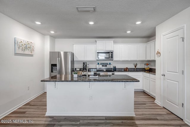 kitchen with appliances with stainless steel finishes, a breakfast bar, an island with sink, and white cabinets