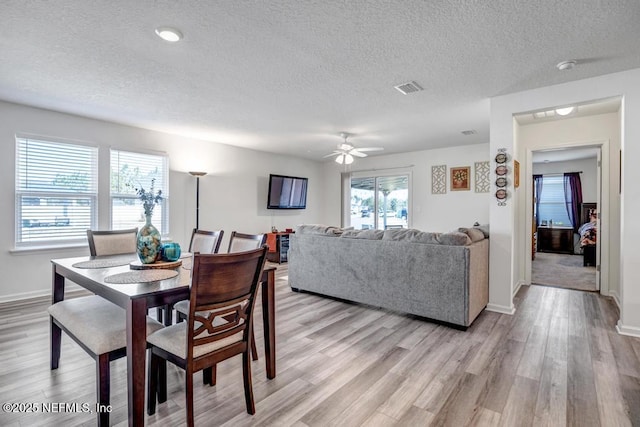 dining space featuring ceiling fan, a textured ceiling, and light hardwood / wood-style flooring