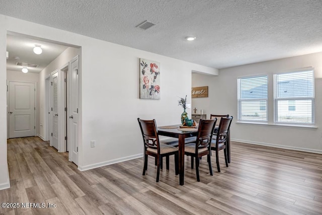 dining area featuring light hardwood / wood-style floors and a textured ceiling