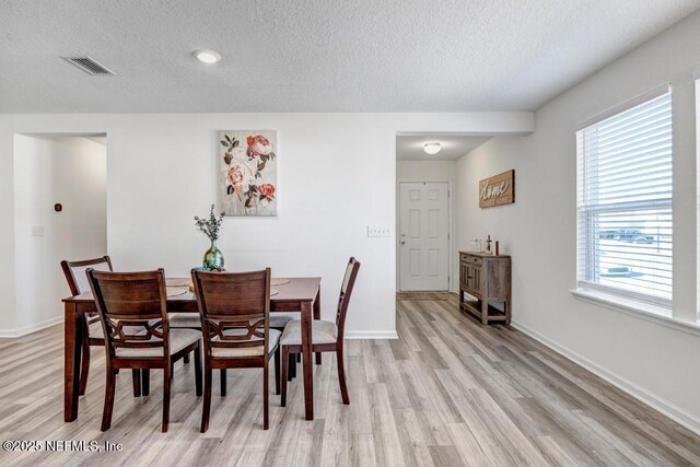 dining area featuring light hardwood / wood-style floors and a textured ceiling