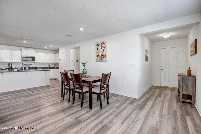 dining space with light hardwood / wood-style flooring and a textured ceiling